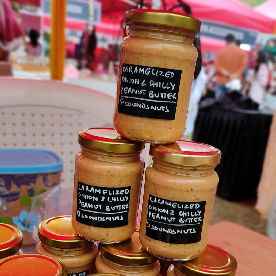 Stack of jars of unique peanut butter with labels on a blurred background