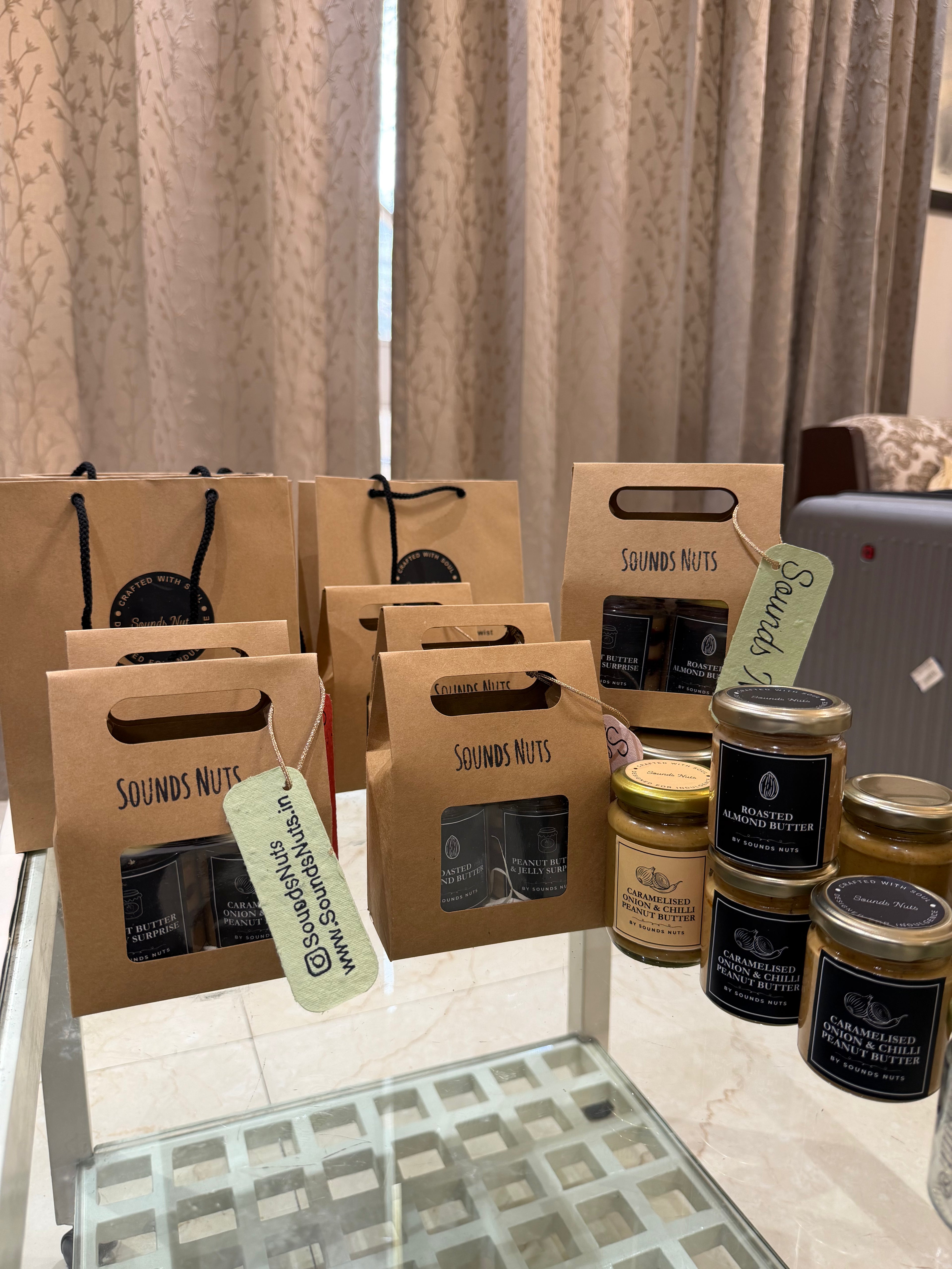 Brown gift boxes with 'Sounds Nuts' branding on a table with a neutral curtain background.